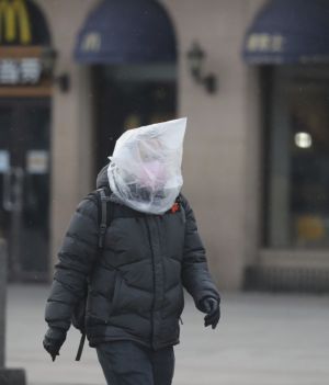 Mężczyzna w masce owiniętej plastikową torbą idzie na stację kolejową w Pekinie 5 lutego 2020 r. fot. Yomiuri Shimbun/Associated Press/East News