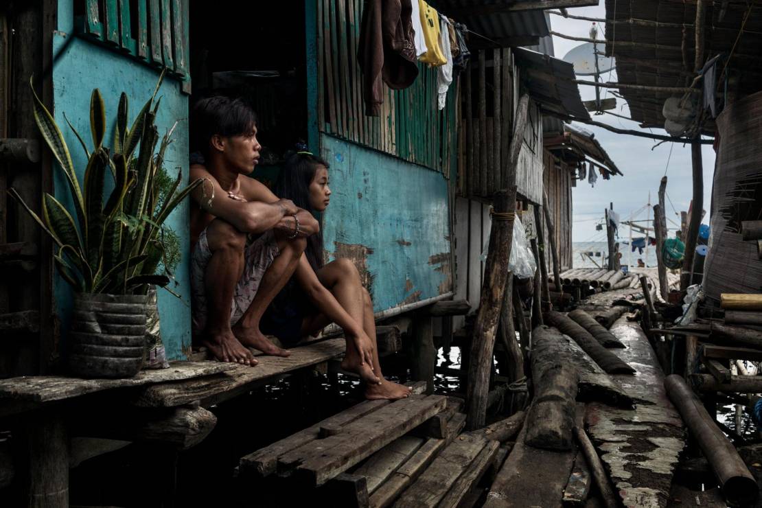 Para siedzi przed domem zbudowanym nad wodą w Quezon