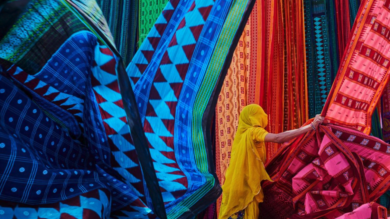W fabryce sari w Radżastanie pracownica wiesza świeżo ufarbowane tkaniny na słońcu, aby wyschły przed złożeniem ich do transportu (PHOTOGRAPH BY TUUL AND BRUNO MORANDI)